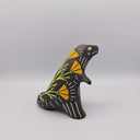 Matte finish ceramic sculpture of a T-Rex dinosaur, black with cream colored sgraffito line detailing and golden poppy flower designs on its back.