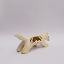 A cream colored ceramic wolf, with an opening in its body that holds gold charms, hanging from wire. Surrounded the opening are ceramic vine shapes.