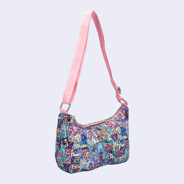 Shoulder purse with a long strap. Features pastel pink colored fabric detailing, around the zipper and as the handles/straps. Bag has a small "tokidoki" nameplate on the center and is covered completely in a busy colorful pattern featuring tokidoki characters with with galactic and sci fi imagery.