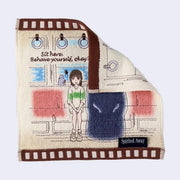 Cream colored hand towel with brown square outline. Embroidered on is a scene from Spirited Away with the characters sitting on a train with text that reads, "Sit here. Behave yourself, okay?"