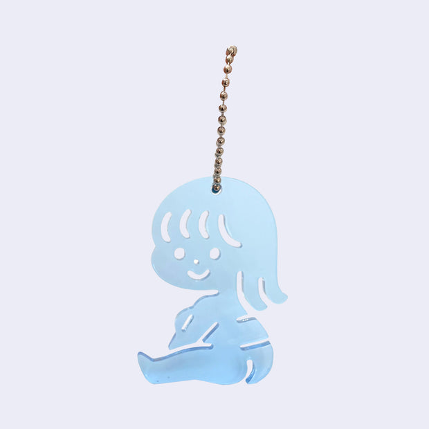 Blue acrylic charm of a small cartoon girl sitting down and smiling. It is attached to a ball chain.