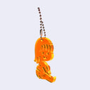 Orange acrylic charm of a small cartoon girl sitting down and smiling. It is attached to a ball chain.