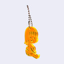 Yellow acrylic charm of a small cartoon girl sitting down and smiling. It is attached to a ball chain.