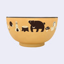 Yellow bowl with cream and brown colored illustrations of forest animals (bear, hedgehog, squirrel, bunny) and forest greenery (mushroom, tree stumps, flowers)