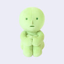 Green plush toy with a simple face on a light gray background