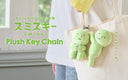 Green plush keychains attached to a tote bag with SMISKI branding.