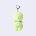 Green plush keychain of Smiski, sitting with its knees pulled into its chest.