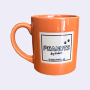 Orange mug with a 'Peanuts' label on a light gray background