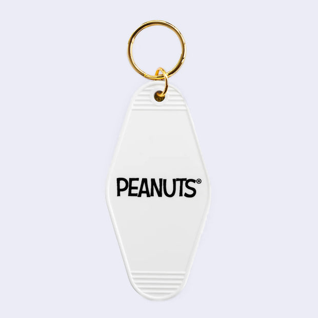 Back view of key tag, white diamond shaped with rounded edges and text that reads "Peanuts"