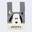 Tote bag with a design of Snoopy's face, looking straight on with a star and moon above him. Tote is gray with beige color accents.