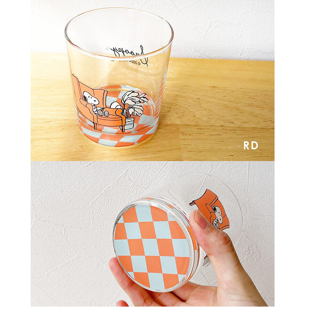 Glass tumbler with checkered design at the bottom that can be seen from overhead and below, and a graphic of Snoopy sitting in a chair.