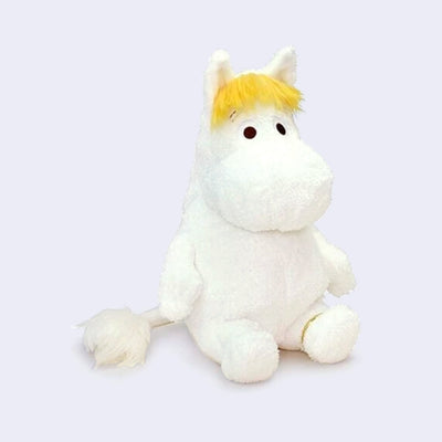 White Moomin plush toy with yellow hair and a gold ring around her ankle.