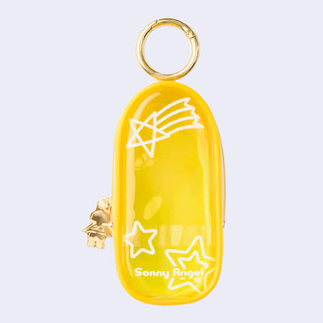 Yellow clear colored oval shaped pouch attached to a keychain, with gold keychain hardware and a small golden Sonny Angel on the side. White line doodles decorate the exterior.