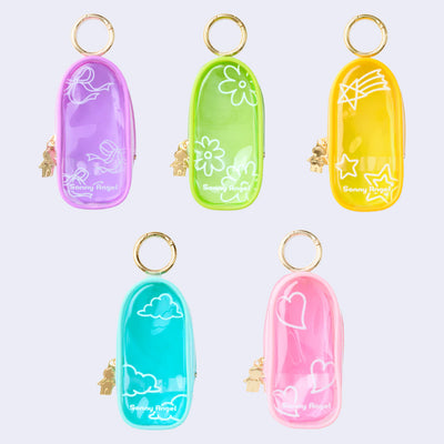 5 clear colored oval shaped pouches attached to keychains, with gold keychain hardware and a small golden Sonny Angel on the side. Colors are: purple, green, yellow, blue and pink.