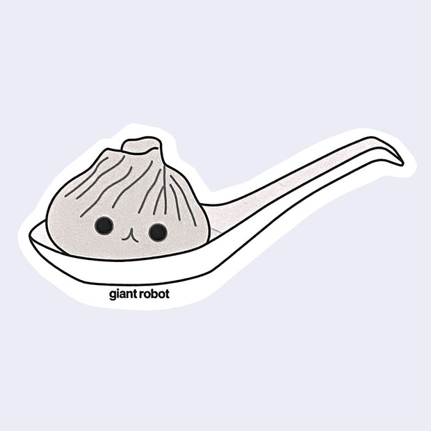 Die cut sticker of an illustrated soup dumpling in a large ramen spoon. Dumpling has a smiling face.