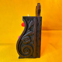 Side view of carved wooden shelf.