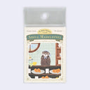 A pack of 'A Sea Otter and Shell Madeleines' sticky notes in a clear plastic sleeve, featuring an illustration of an otter at a bakery counter with pastries.