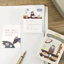 Notebook with stationery items featuring otters on a wooden surface