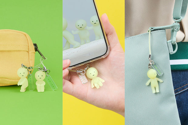 Promo graphic for Smiski: Strap Accessories capsule of several Smiskis attached to a string strap and tied to bags or a cell phone.