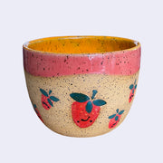 Ceramic bowl with spotted finishing and an earthy brown exterior and orange interior. On the outside are painted on cartoon style strawberries, with simple expressions.