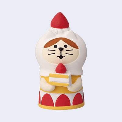 Figure of a brown and white cat holding a strawberry cake slice and wearing a strawberry shortcake layered dress with a strawberry atop her head.