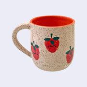 Ceramic mug with spotted finishing and an earthy brown exterior and pinkish red interior. On the outside are painted on cartoon style strawberries, with simple expressions.