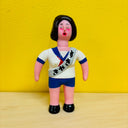 Toy figure with a white shirt and blue shorts against a yellow background