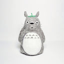 Needle felted wool sculpture of Totoro, standing with a curious expression on his face and arms by his side. He has a leaf atop his head and stiff whiskers.