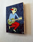 Painting of a bird-like character playing a guitar on a blue background with leaf patterns.