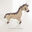 Ceramic horse figurine, beige in color with detailing of purple for its mane, eyes, hooves and snout.