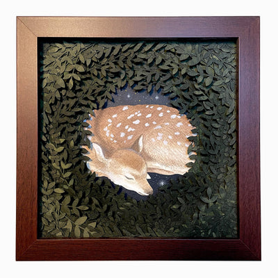 Layered cut paper diorama style sculpture in an open wooden frame, with many layers of leaves revealing a small scene of a sleeping doe.