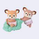 2 small deer dolls with flocked fur, dressed in little outfits for children. One pushes the other on a green train car.