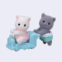 Two small cat figurines, one white and one gray, with a blue toy car on a light purple background.