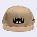 Beige cap with a black and white graphic on a light gray background