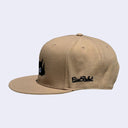 Beige cap with black logo on a light gray background
