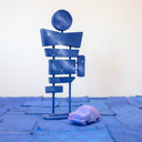 Pair of 2 carved wooden sculptures: a small retro looking purple car with 81 drawn on the side, and a large signpost with 7 different signs, though all painting like a dark blue night sky without any words.