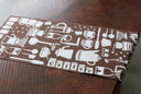Brown towel with white coffee-themed patterns on a wooden surface
