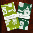 Two green and white patterned fabric napkins with 'IKS Collection' branding on a wooden surface.