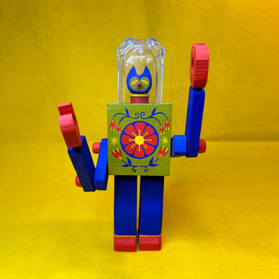 Colorful toy wooden robot with a floral design on the chest and a clear helmet. A tiny cat head is inside the helmet.