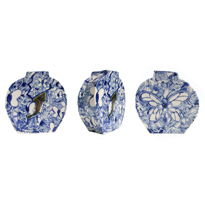 A blue and white colored ceramic vase, with butterflies painted around it in addition to other nature motifs. In the front center is a visual chasm, which one butterfly stands outside of.