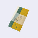 Folded towel with green and yellow pattern on a light gray background