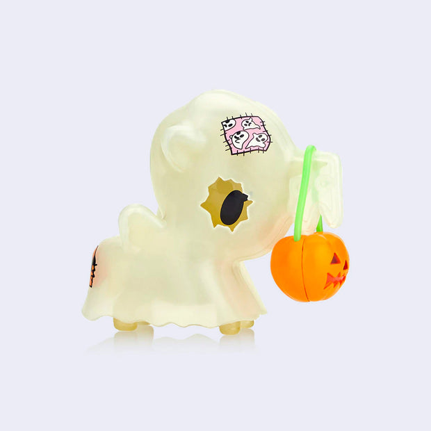 "Boo!" unicorn figure, cloaked in a semi transparent sheet like a ghost. It has a single cut out for its eyes. Draped over its horn is a jack o lantern shaped basket, for trick or treating.