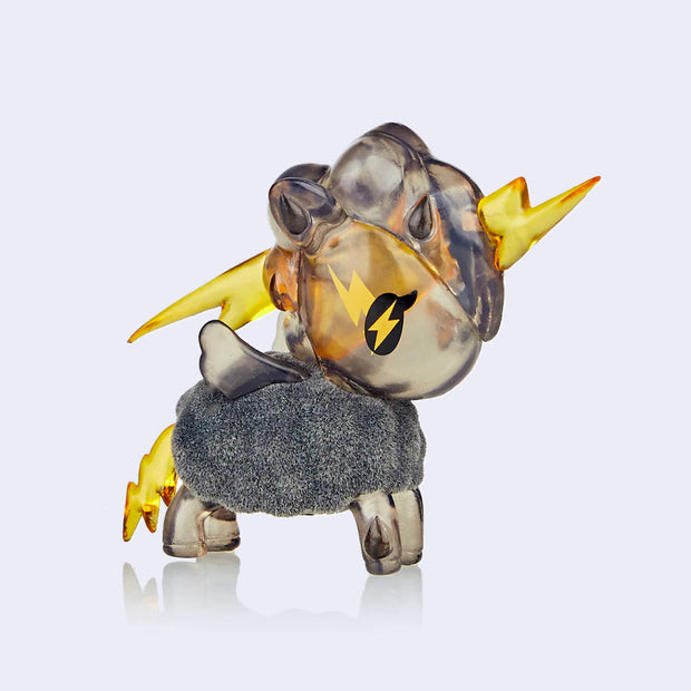 A semi transparent grey vinyl unicorn figure with a large lightning bolt going through its head and a smaller one as its tail. Its body is flocked and fluffy, like a grey cloud.