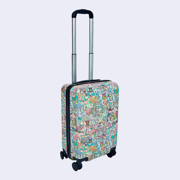 Hardcover suitcase, rounded edges, covered completely in a busy pattern imagery of cute tokidoki characters at a carnival. All characters are decorated in carnival themed attire. Its handle is extended out fully.