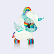 A small white and blue unicorn with rainbow arc atop its head and rainbow patterned legs, tail and partial face. Its body and mane are fluffy and white, like clouds.