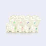 A line of 4 squishy white unicorn figures, with either green, pink, blue or purple eyes. 