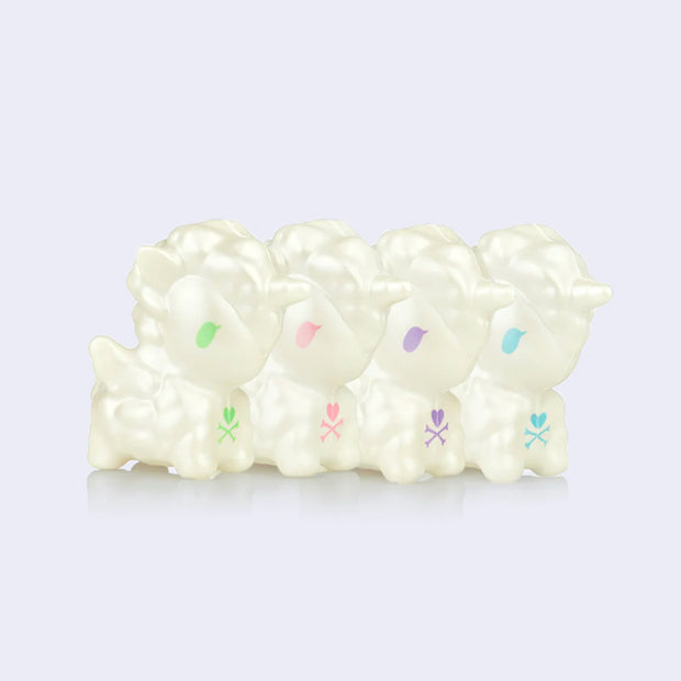 A line of 4 squishy white unicorn figures, with either green, pink, blue or purple eyes. 