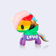 A vinyl unicorn colored like various pride flags, rainbow body with baby pink, blue, bronze and black hair. "Love" is written along the side of the body.