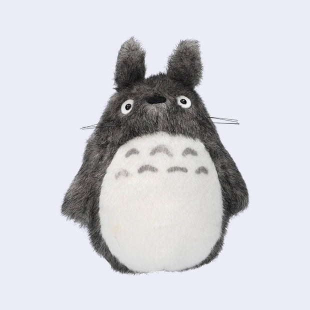 Dark gray Totoro plush, with a large white furry belly and whiskers. He has no mouth.