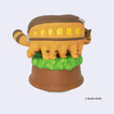 Wind-up music playing figurine of Catbus from My Neighbor Totoro, standing atop a greenery on a wooden looking base. Catbus is smiling with a slight curve in its stance. Back view.